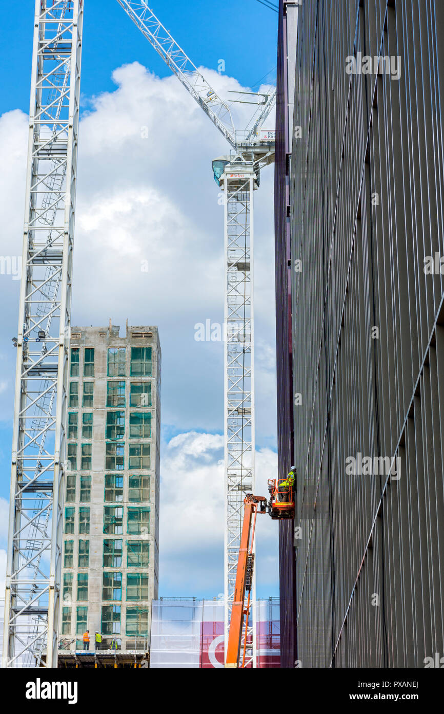 Un lavoratore su una piattaforma aerea e gru a torre, presso il Circolo quadrato e ufficio sviluppo residenziale, Oxford Road, Manchester, Inghilterra, Regno Unito Foto Stock