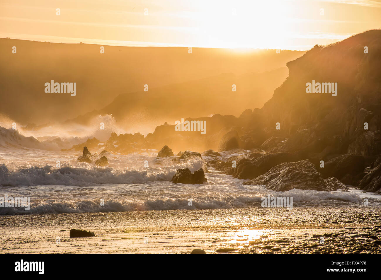 Golden Sunset over Pembrokeshire costa rocciosa,spruzzi delle onde e la brezza della sera,scogliere e la nebbia in background.paesaggio panoramico Uk.Magic ora sulla spiaggia. Foto Stock