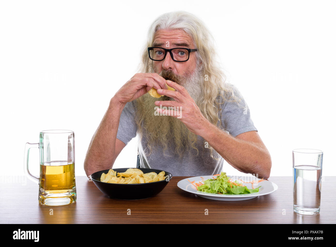 Studio shot di senior uomo barbuto mangiare patatine con healt Foto Stock
