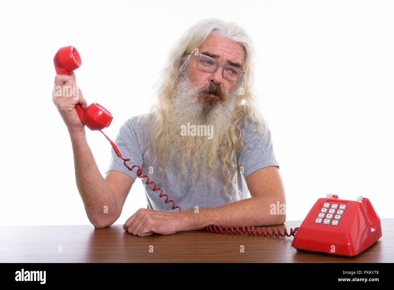 Studio shot di senior uomo barbuto tenendo il vecchio telefono mentre lo Foto Stock