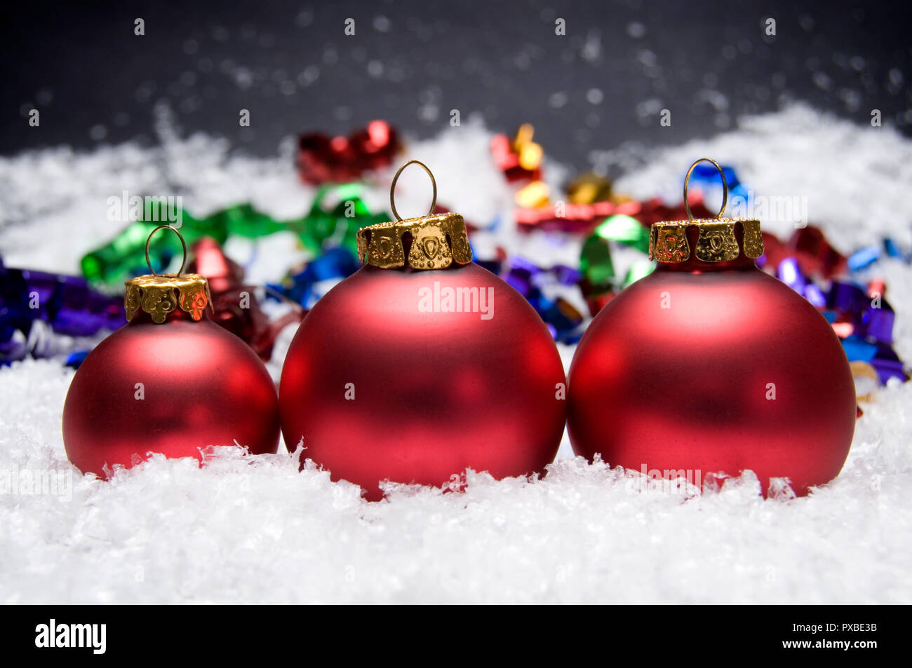 Meraviglioso rosso palle di Natale con la neve su uno sfondo scuro Foto Stock