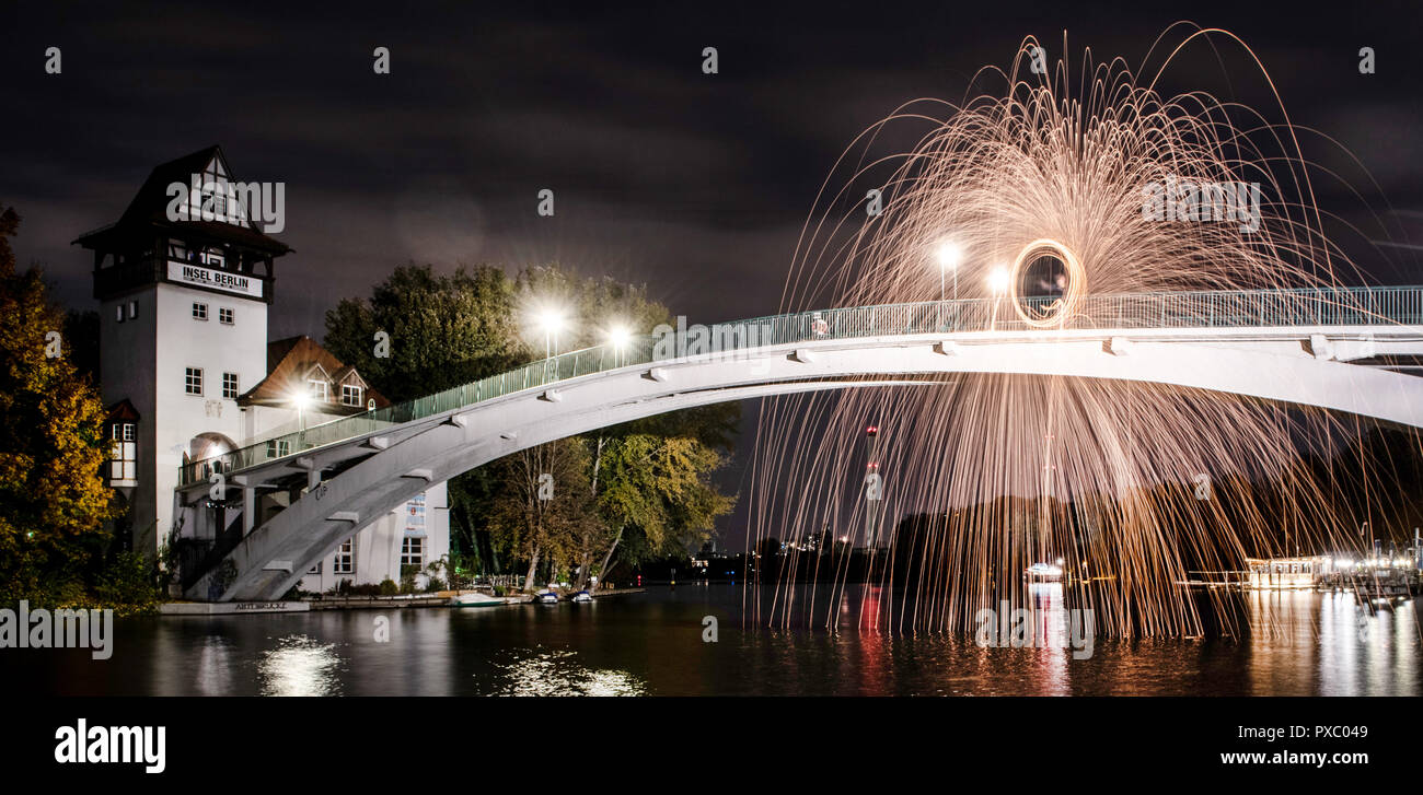 Berlino, Germania. Xx oct, 2018. Un uomo si erge sul ponte per l'Isola della Gioventù e evoca un cerchio di fuoco nel cielo di sera. Credito: Paolo Zinken/dpa/Alamy Live News Foto Stock