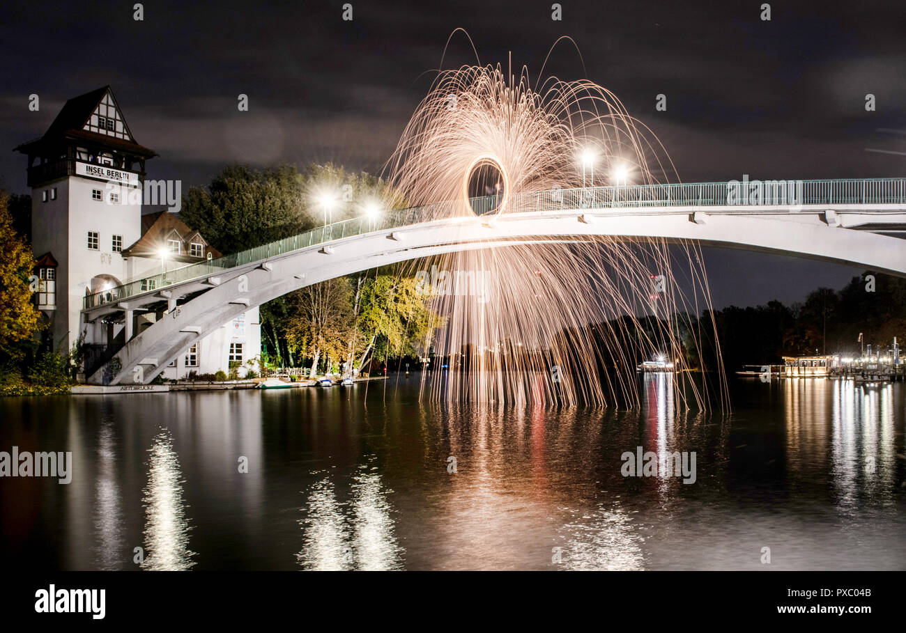 Berlino, Germania. Xx oct, 2018. Un uomo si erge sul ponte per l'Isola della Gioventù e evoca un cerchio di fuoco nel cielo di sera. Credito: Paolo Zinken/dpa/Alamy Live News Foto Stock