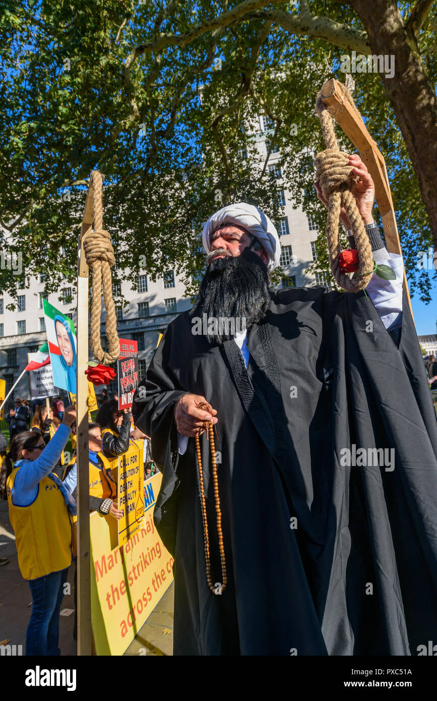 Londra, Regno Unito. 20 ott 2018. Un uomo vestito come un ayatollah accarezza il nodo su un cappio. Dietro un banner "democrazia in Iran con Maryam Rajavi', Mujaheddin del popolo dell'Iran terrà una manifestazione di protesta contro la repressione del regime attuale in Iran con un patibolo e tre donne detenute in una cella di prigione che illustra il regno del terrore vi e per chiedere la fine delle esecuzioni ci, . Credito: ZUMA Press, Inc./Alamy Live News Foto Stock