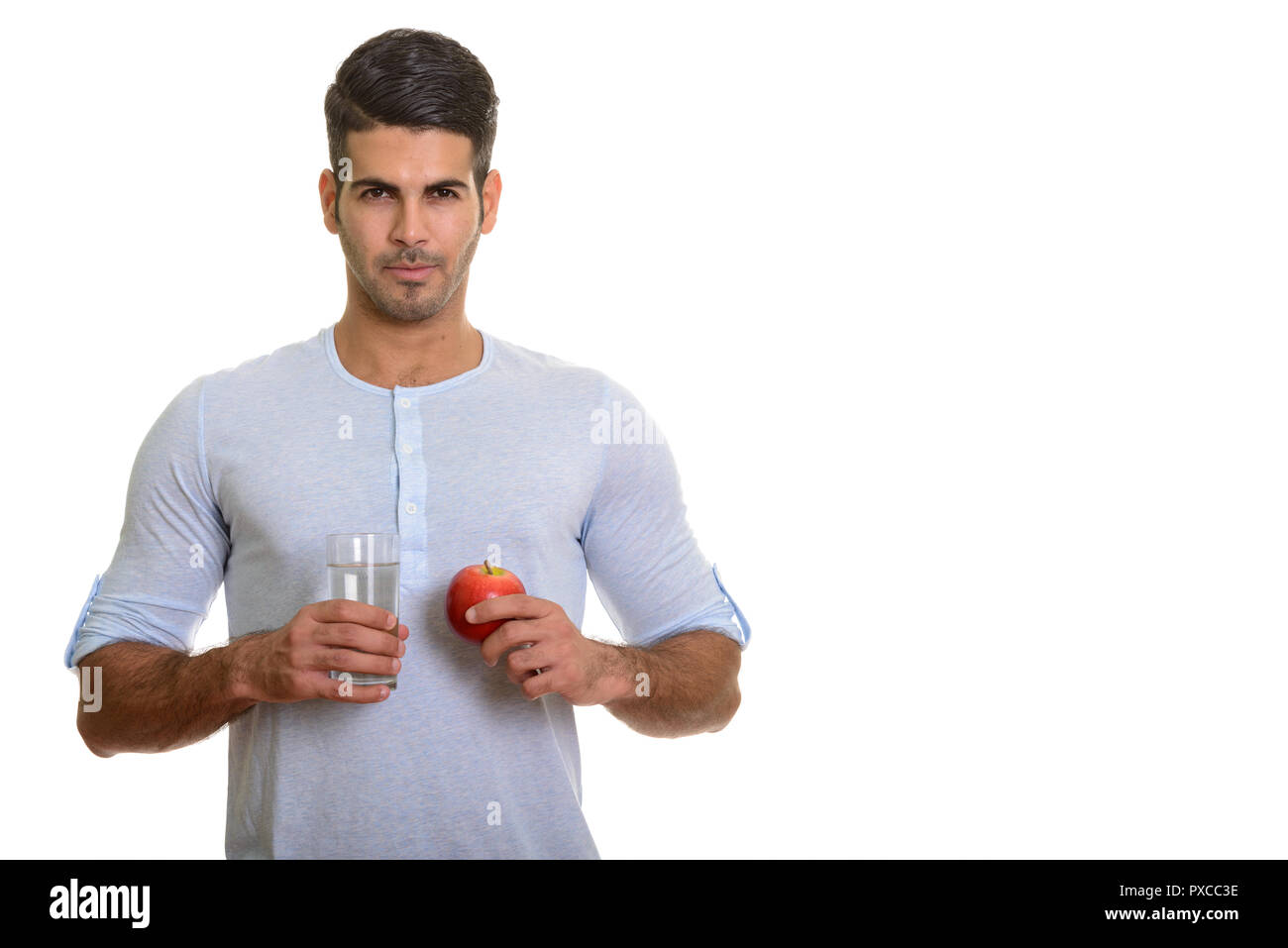 Bel giovane uomo persiano tenendo un bicchiere di acqua e mela rossa Foto Stock