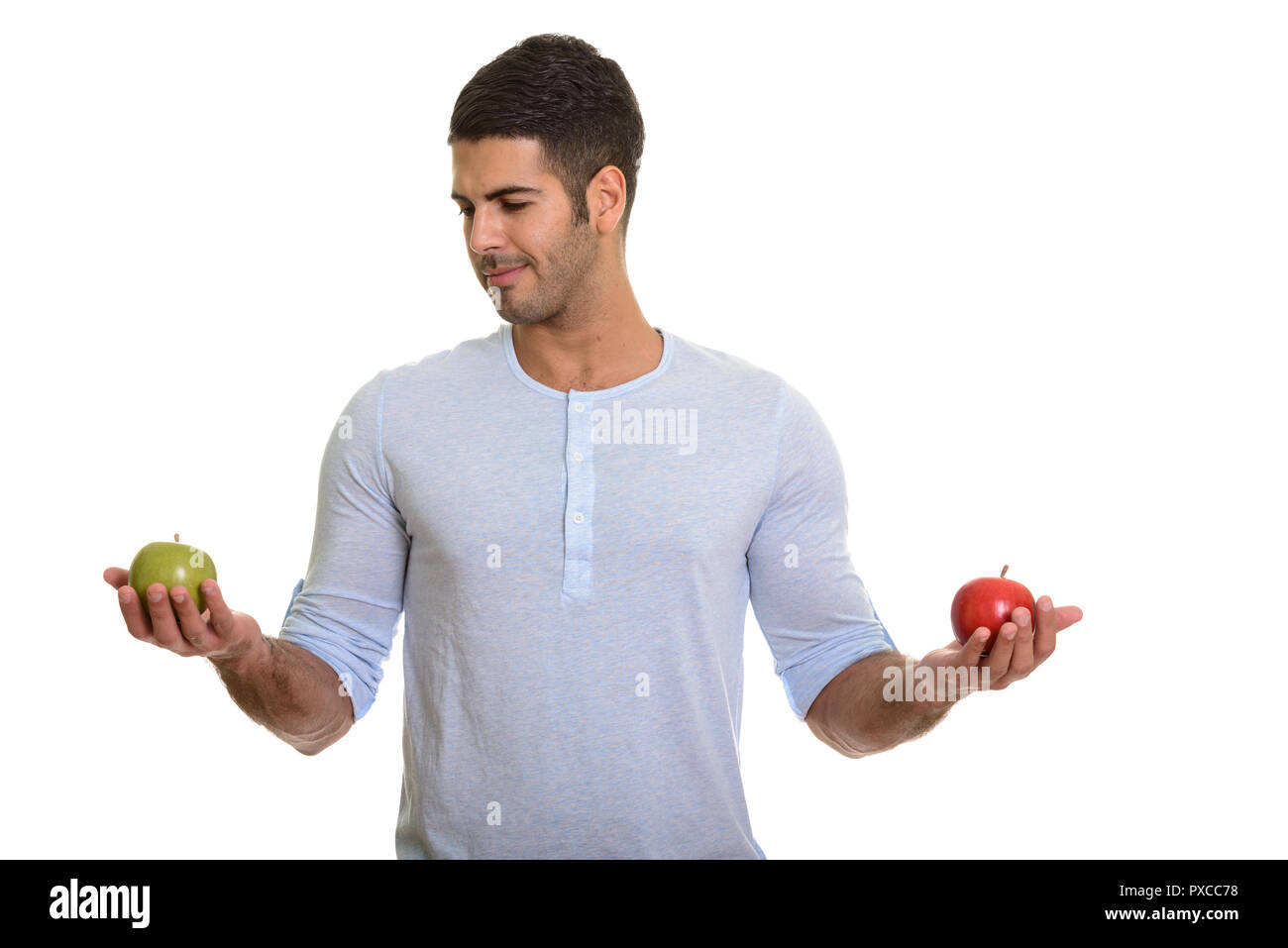 Bel giovane uomo persiano scegliendo tra rosso e verde mela Foto Stock