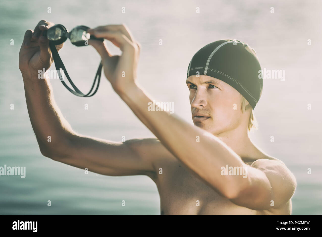 Nuotatore modello in un mare guardando attraverso googles al tramonto Foto Stock
