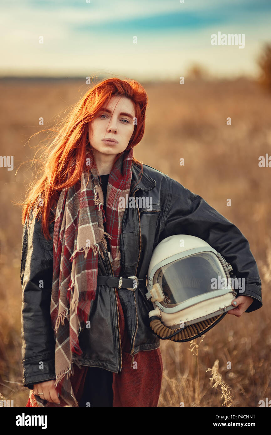 Ritratto di giovane ragazza redhead in nero giacca di pelle e casco di volo all'aperto Foto Stock