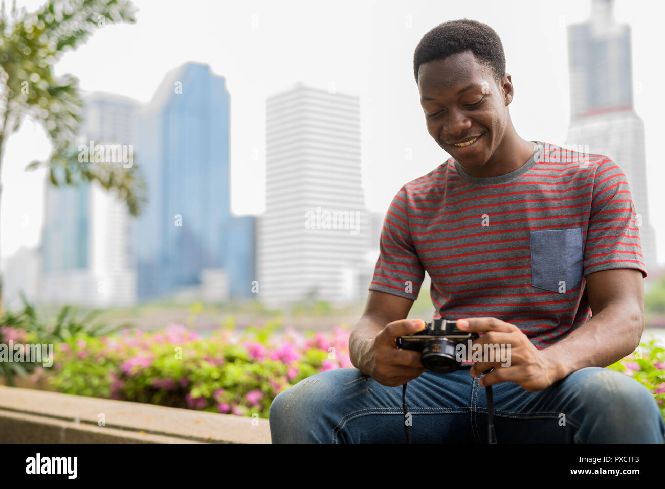 L'uomo africano fotografo alla ricerca di immagini da fotocamera in posizione di parcheggio Foto Stock