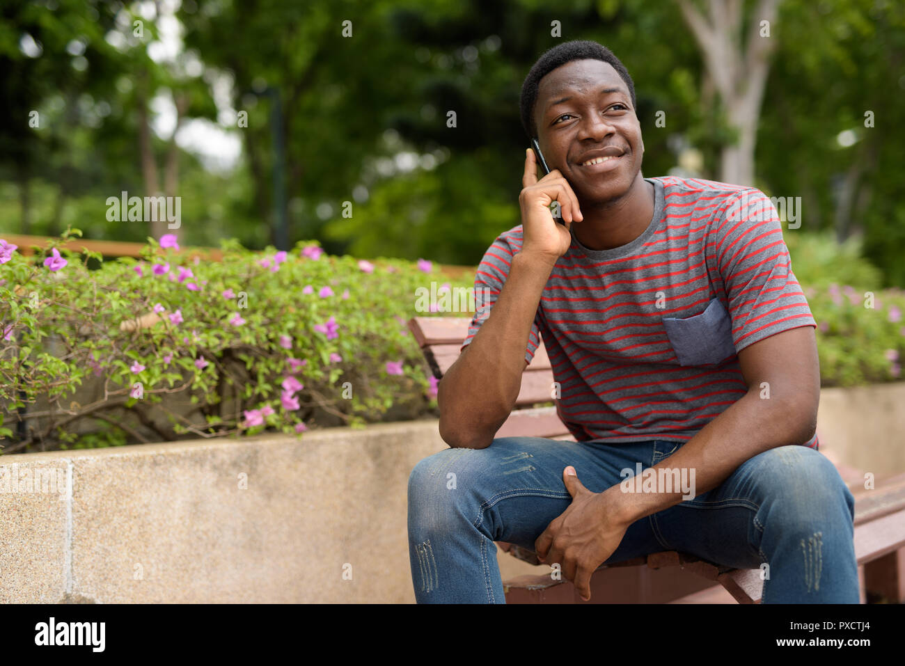Felice l'uomo africano parlando al telefono nel parco Foto Stock