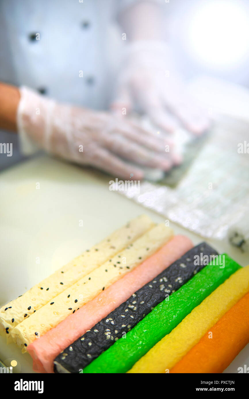 Il processo per la fabbricazione di sushi al ristorante. Nel telaio - le mani del cuoco. Foto Stock