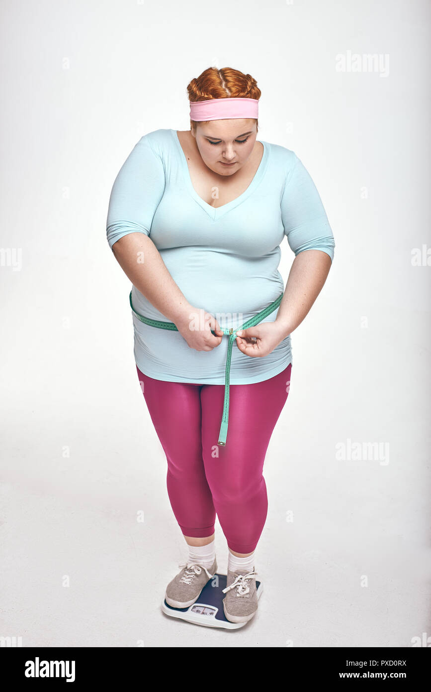 Foto di chubby donna su sfondo bianco. La donna è la misura del suo ventre Foto Stock