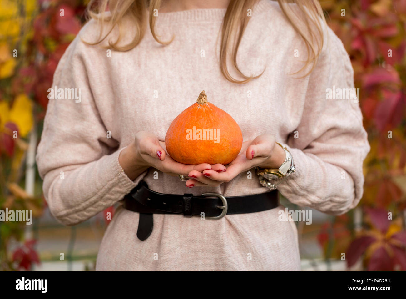 Giovane donna tenere in mano di colore arancione zucca in posizione di parcheggio Foto Stock