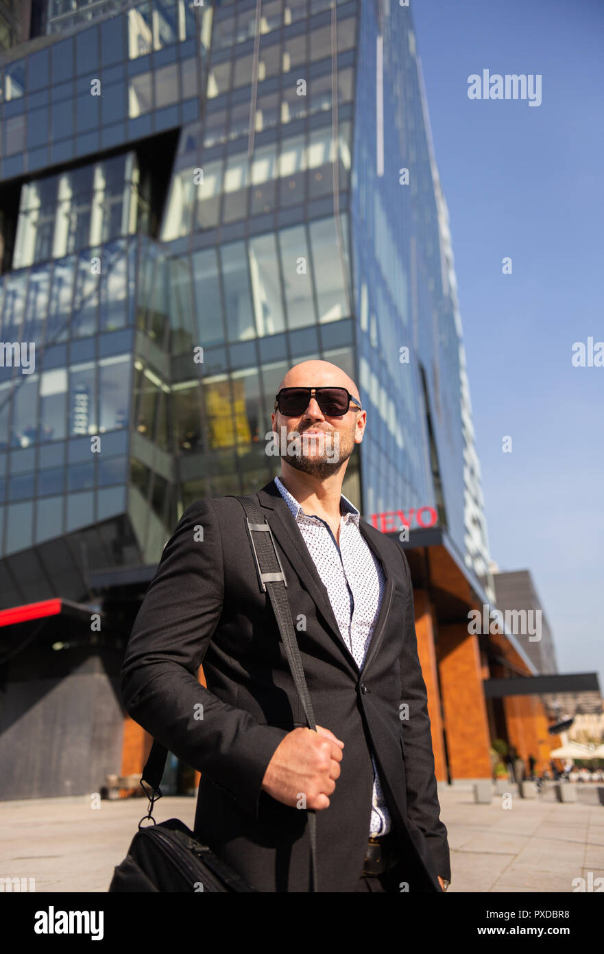 Bello ed elegante imprenditore con occhiali da sole di fronte all edificio per uffici Foto Stock