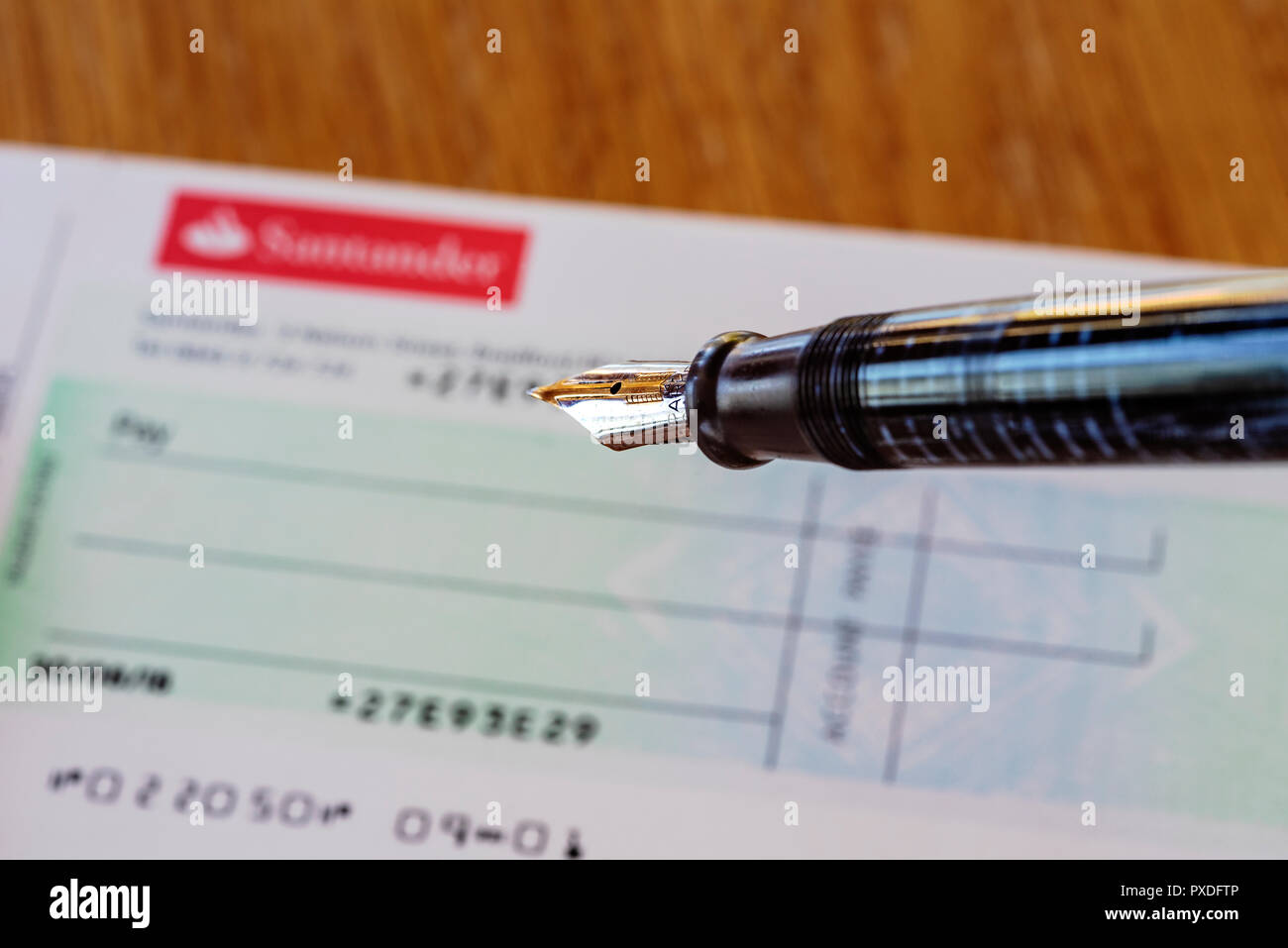 Santander check book e penna stilografica. Retrò o old school banking. La scrittura di un controllo. Foto Stock