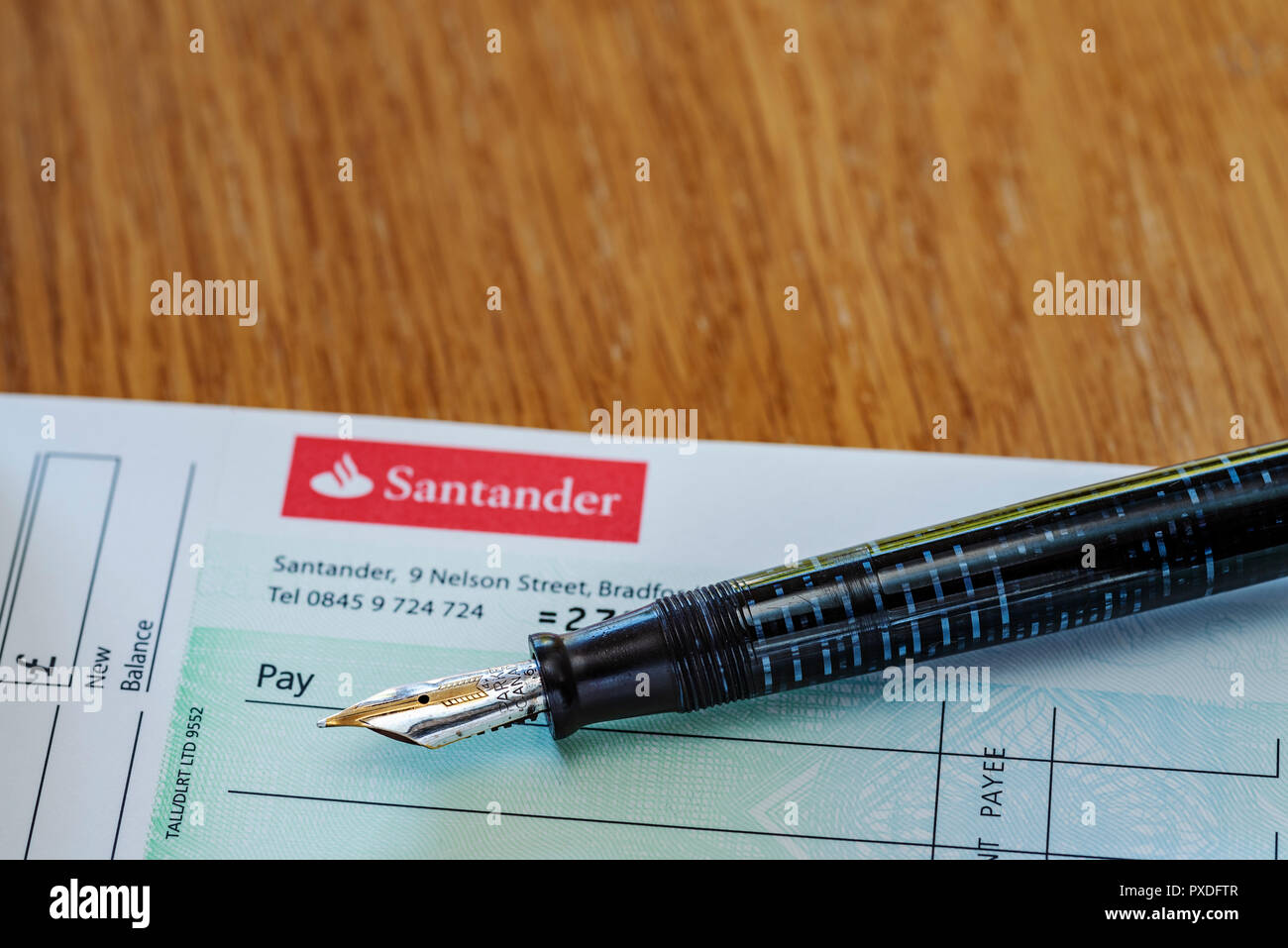 Santander check book e penna stilografica. Retrò o old school banking. La scrittura di un controllo. Foto Stock