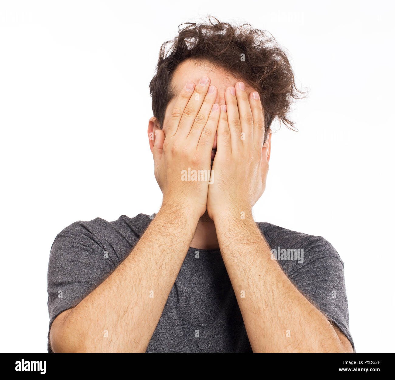 Bello caucasian giovane uomo si copre il viso con le mani Foto Stock