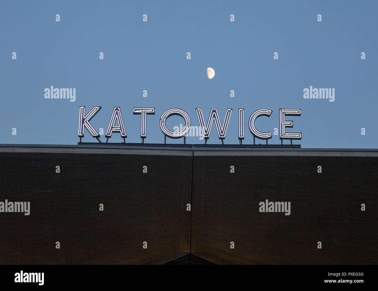 Katowice in Polonia: Katowice insegna al neon sulla parte superiore di una forma a tazza struttura concreta della città stazione ferroviaria oltre il cielo blu e la luna Foto Stock