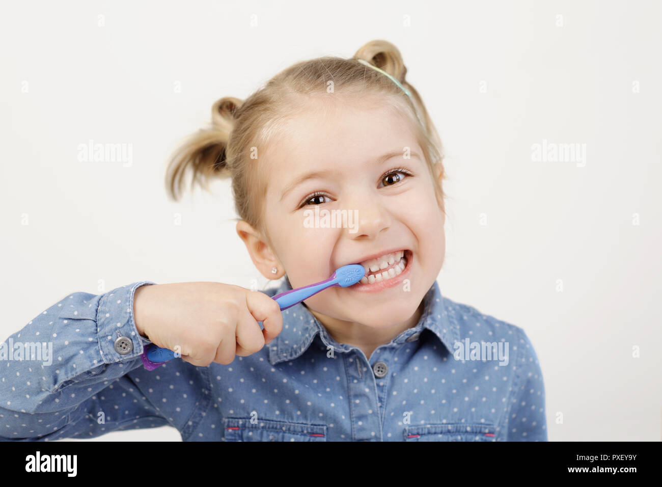 Per le cure dentarie. Carino bambina di cinque anni spazzolare i suoi denti con spazzolino da denti grinning Foto Stock