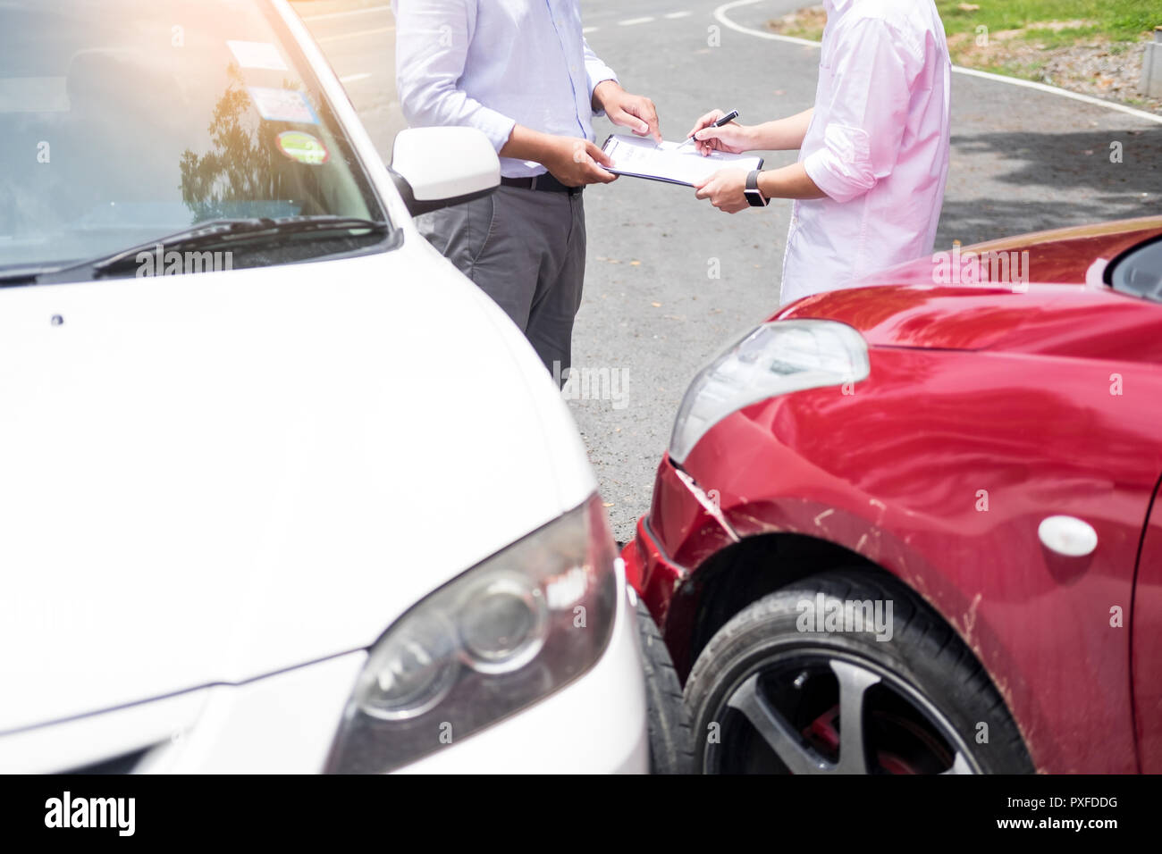 Agente di assicurazione iscritto sulla clipboard mentre esaminando auto dopo incidente rivendicazione essendo valutati ed elaborati Foto Stock