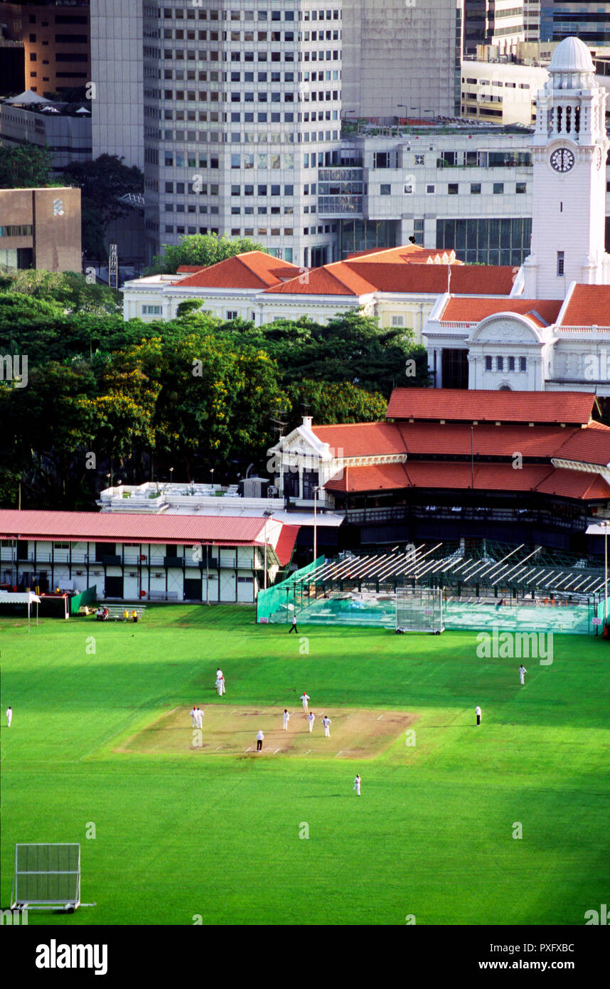 Il cricket che viene riprodotto sulla Padang, Singapore con il quartiere finanziario e la torre dell orologio in background. Foto Stock