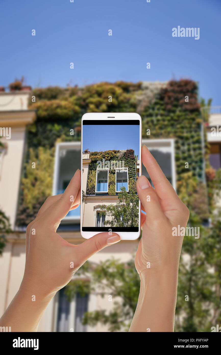 Un turista è di scattare una foto di una città giardino sulla facciata di una delle case in Italia a Roma su un telefono cellulare Foto Stock