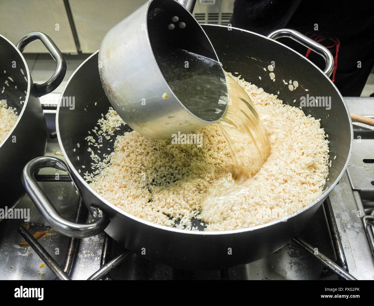 Primi passi della ricetta del risotto : riso tostato e buon brodo , e vino bianco Foto Stock