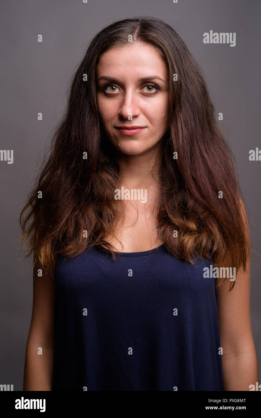 Ritratto di giovane donna bella contro uno sfondo grigio Foto Stock