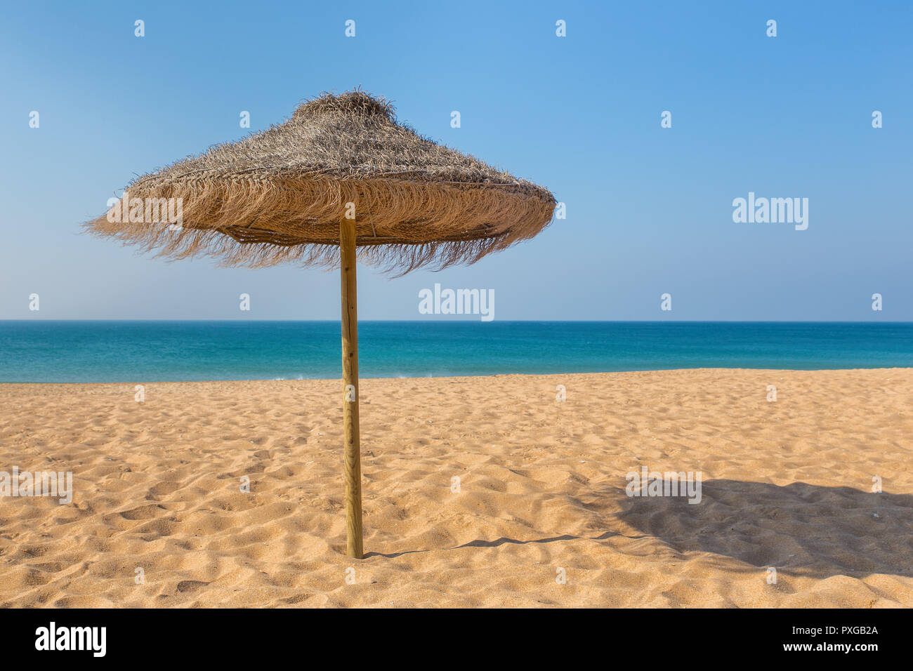Uno di paglia ombrellone in spiaggia al mare blu Foto Stock