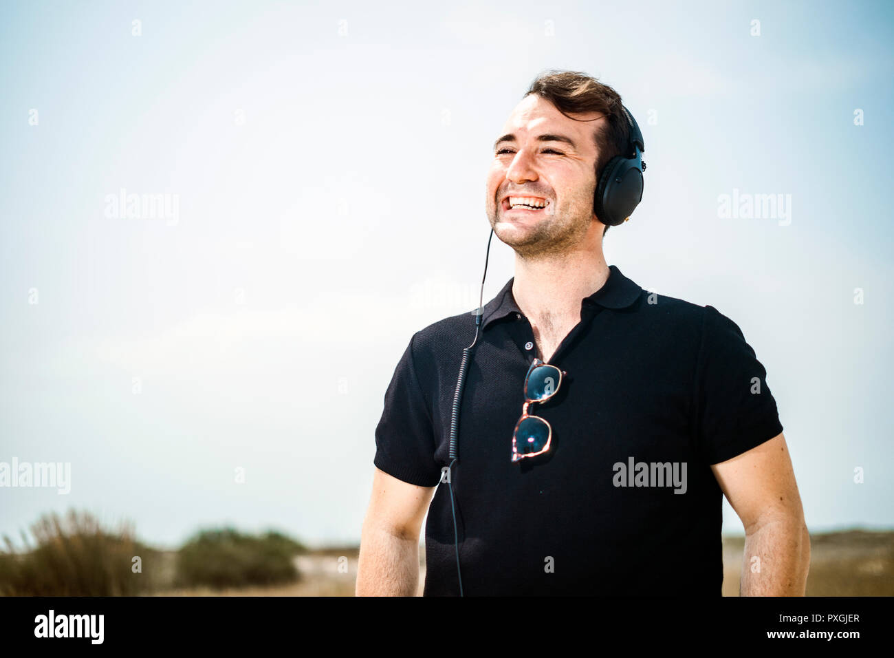 Giovane uomo attraente vestita di nero godendo di musica sul suo cuffie Foto Stock