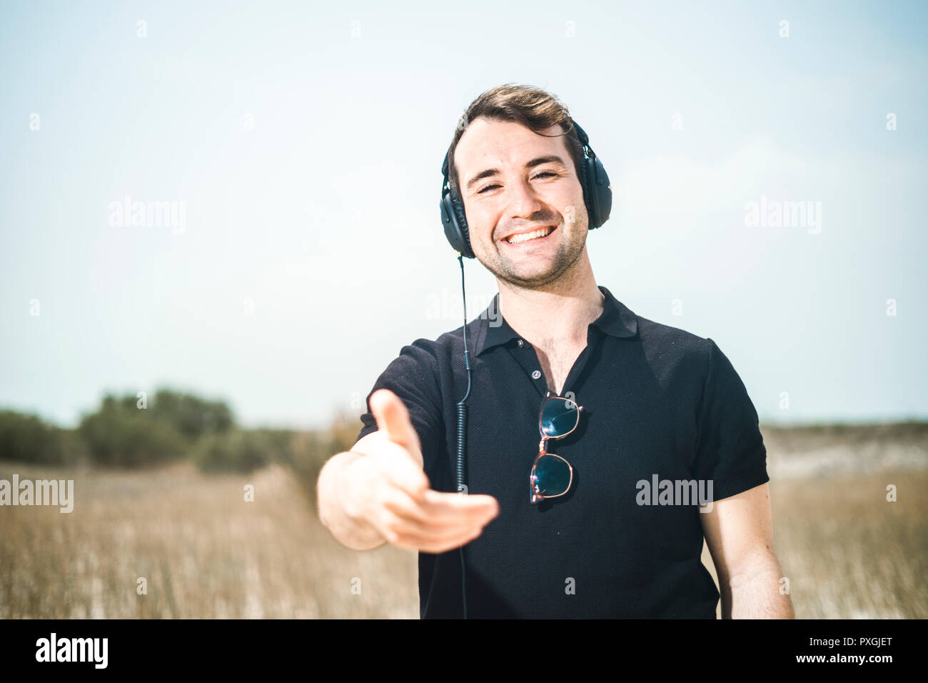 Giovane uomo attraente vestita di nero godendo di musica sul suo cuffie Foto Stock