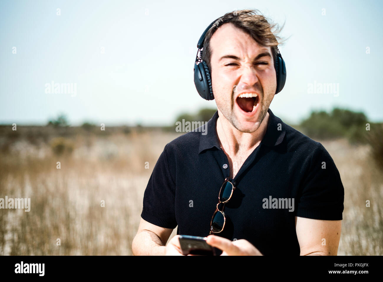 Moda giovane uomo ascolta la musica dal suo smartphone su le sue cuffie Foto Stock