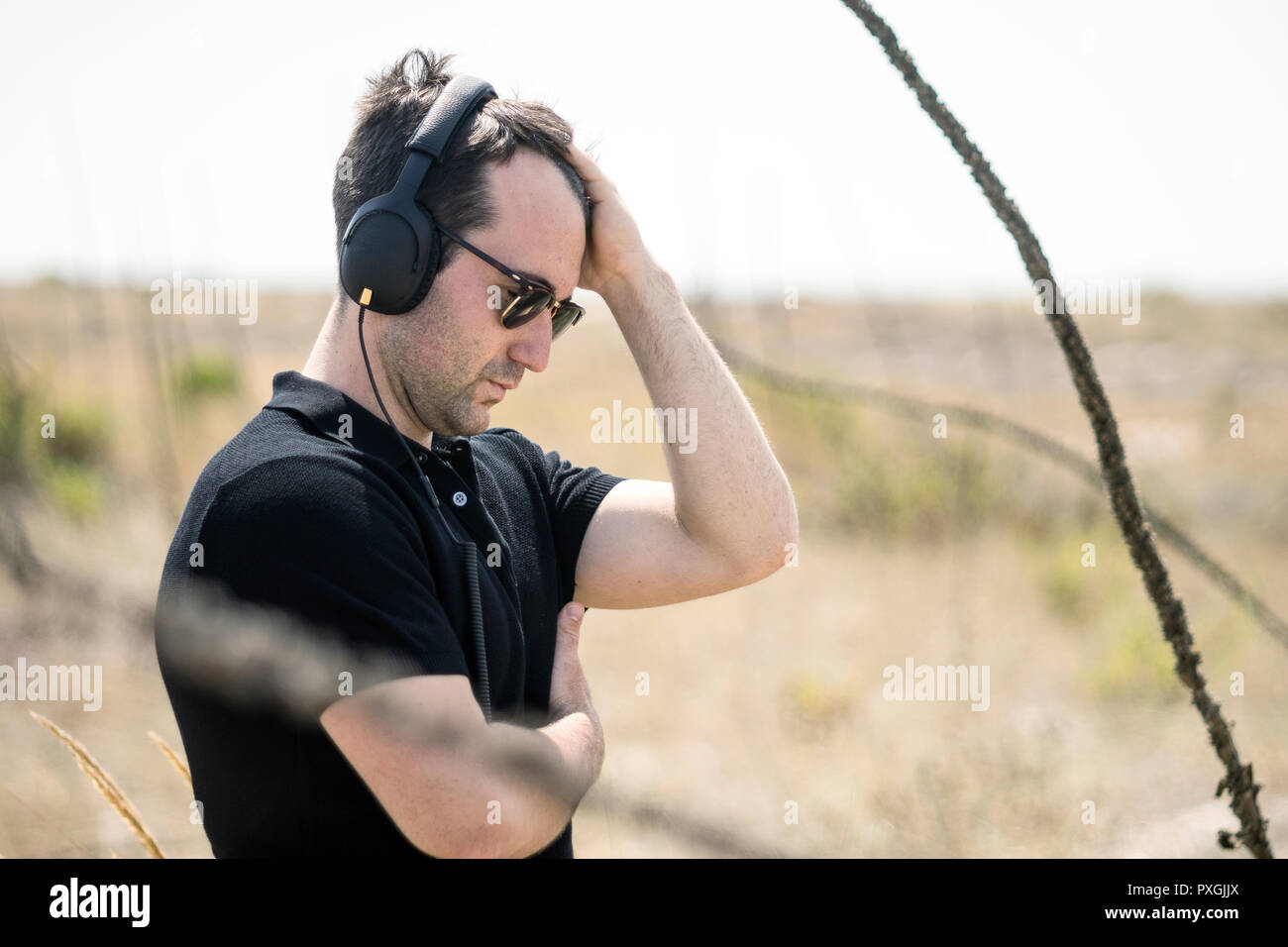 Giovane uomo attraente con occhiali da sole l'ascolto di musica sul suo cuffie Foto Stock