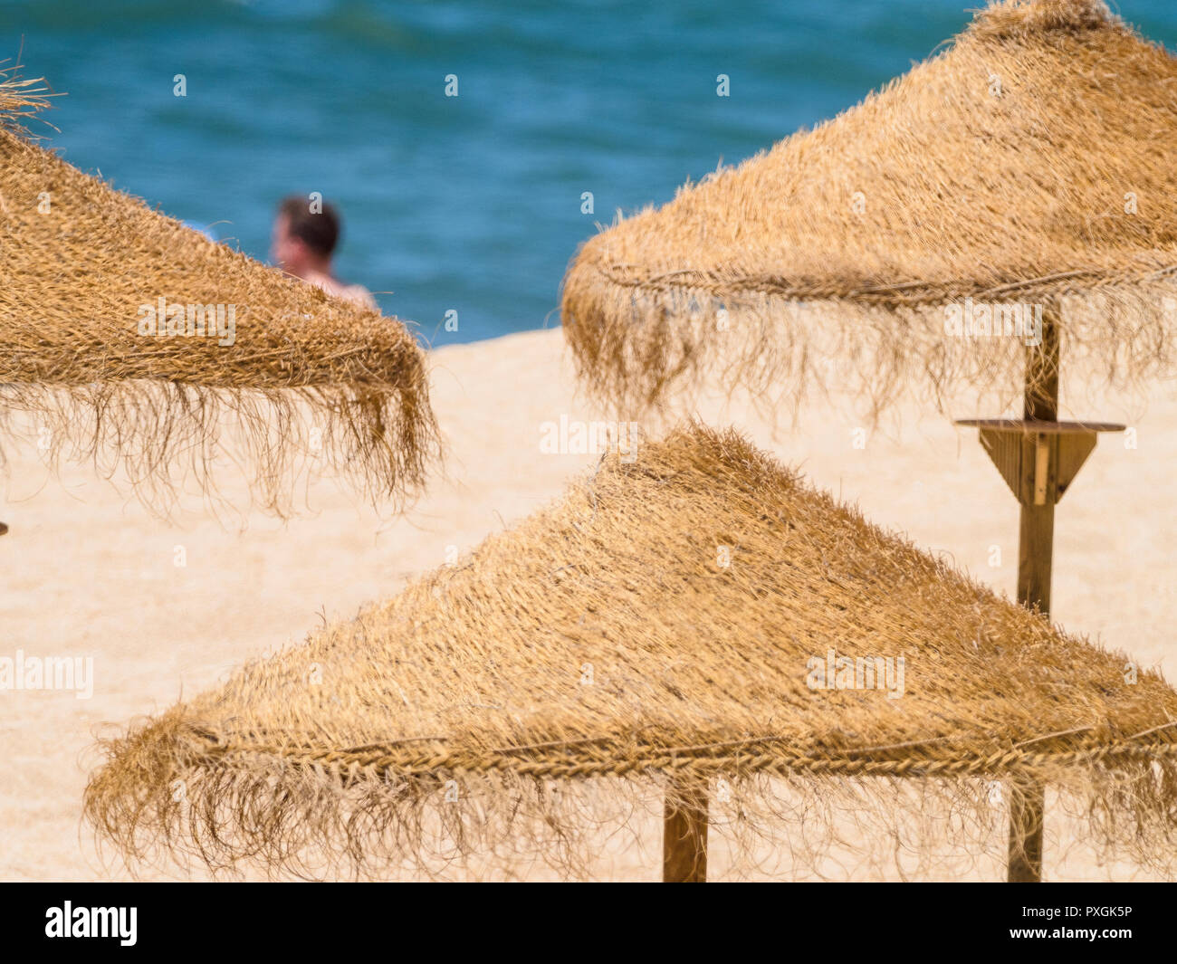 Simbolo di estate - ombrelloni di paglia sulla spiaggia soleggiata del Portogallo Foto Stock