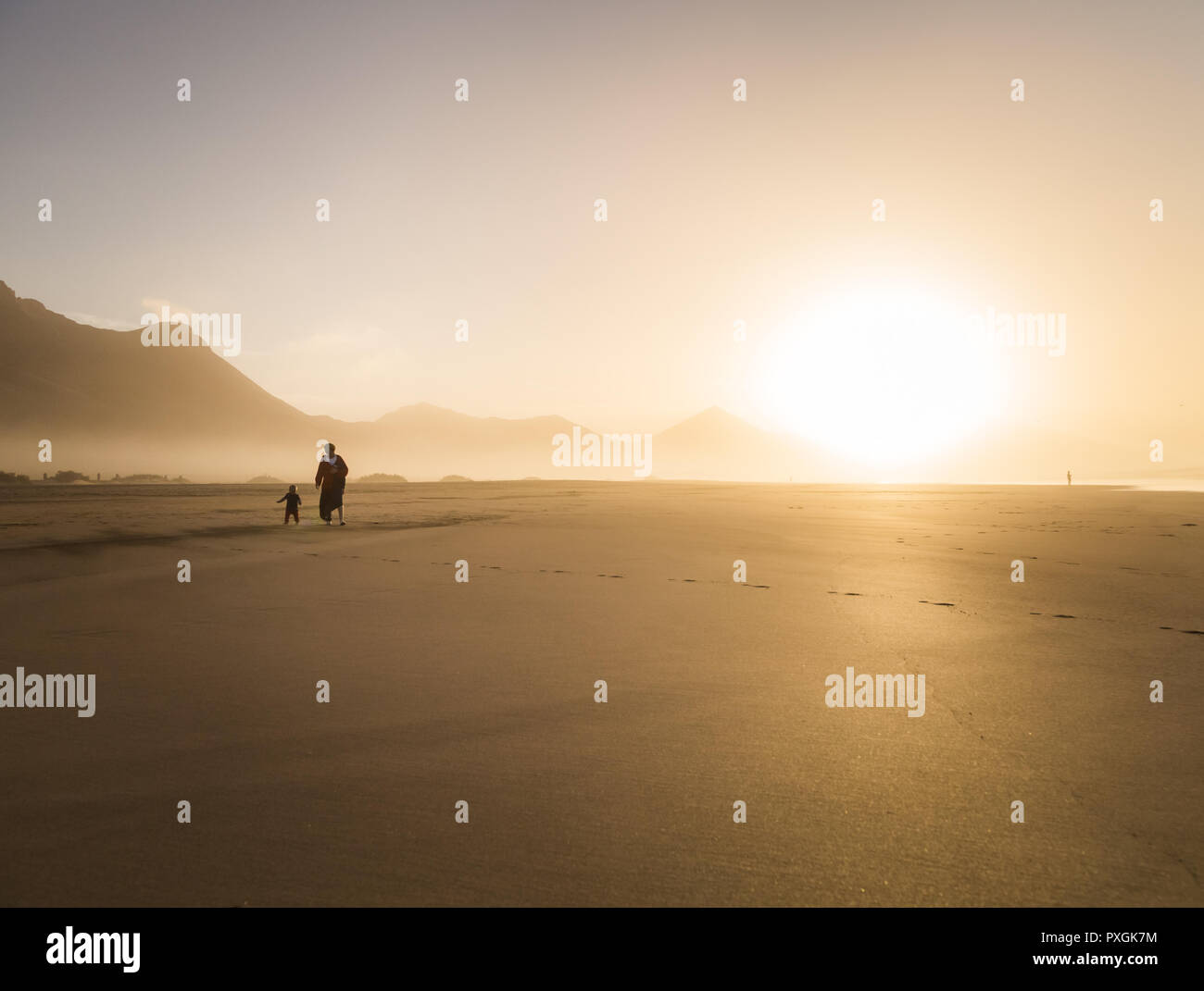 Silhouette di una giovane madre con il suo bambino camminando sul sole di Cofete, Fuerteventura, Isole Canarie, Spagna. Foto Stock