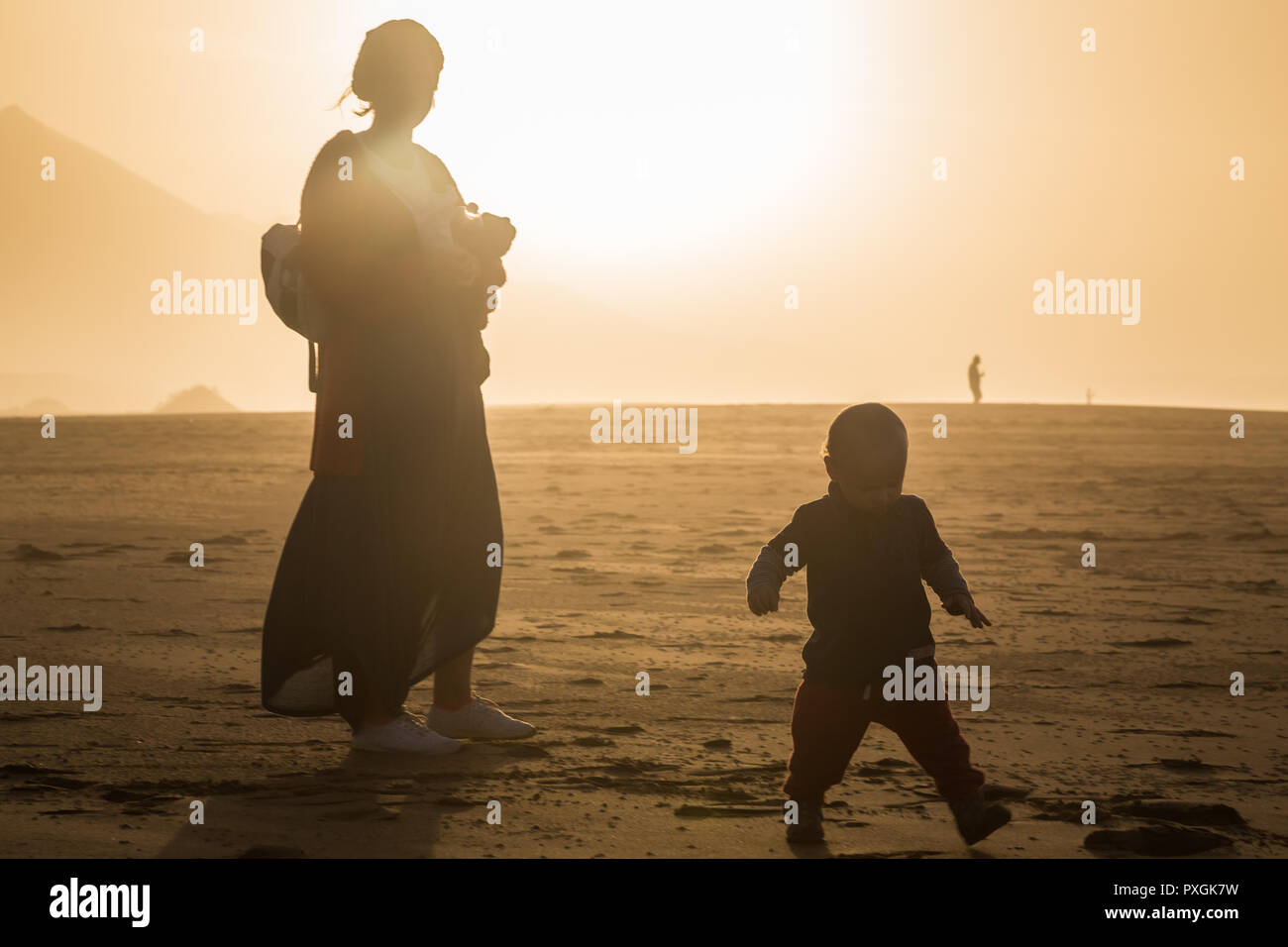Silhouette di una giovane madre con il suo bambino in un giorno di estate in Cofete, Fuerteventura, Isole Canarie, Spagna. Foto Stock