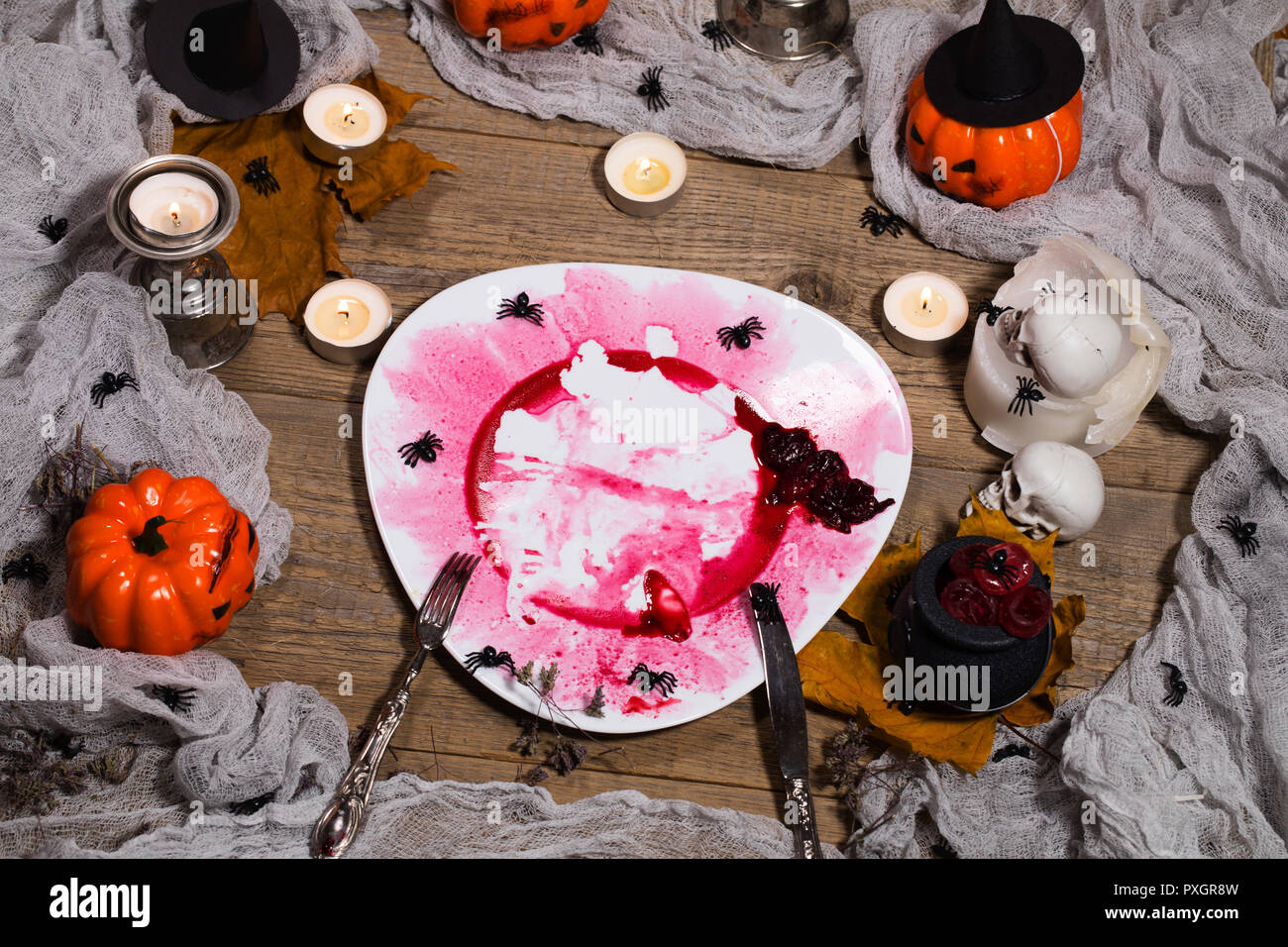 Sporco targhetta rossa con le posate d'argento sulla tavola di Halloween. Primo piano Foto Stock