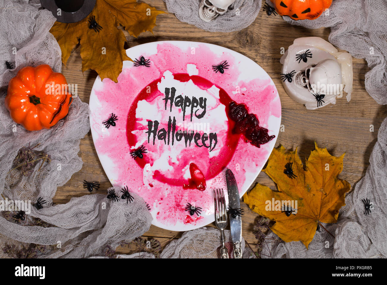 Sporco targhetta rossa con le posate d'argento sulla tavola di Halloween. Primo piano Foto Stock