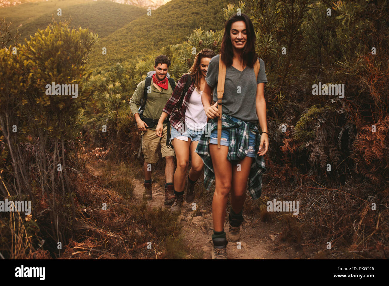 Amici escursionismo sul robusto terreno collinare. Due donne con un amico maschio camminando su un sentiero roccioso su una montagna. Foto Stock