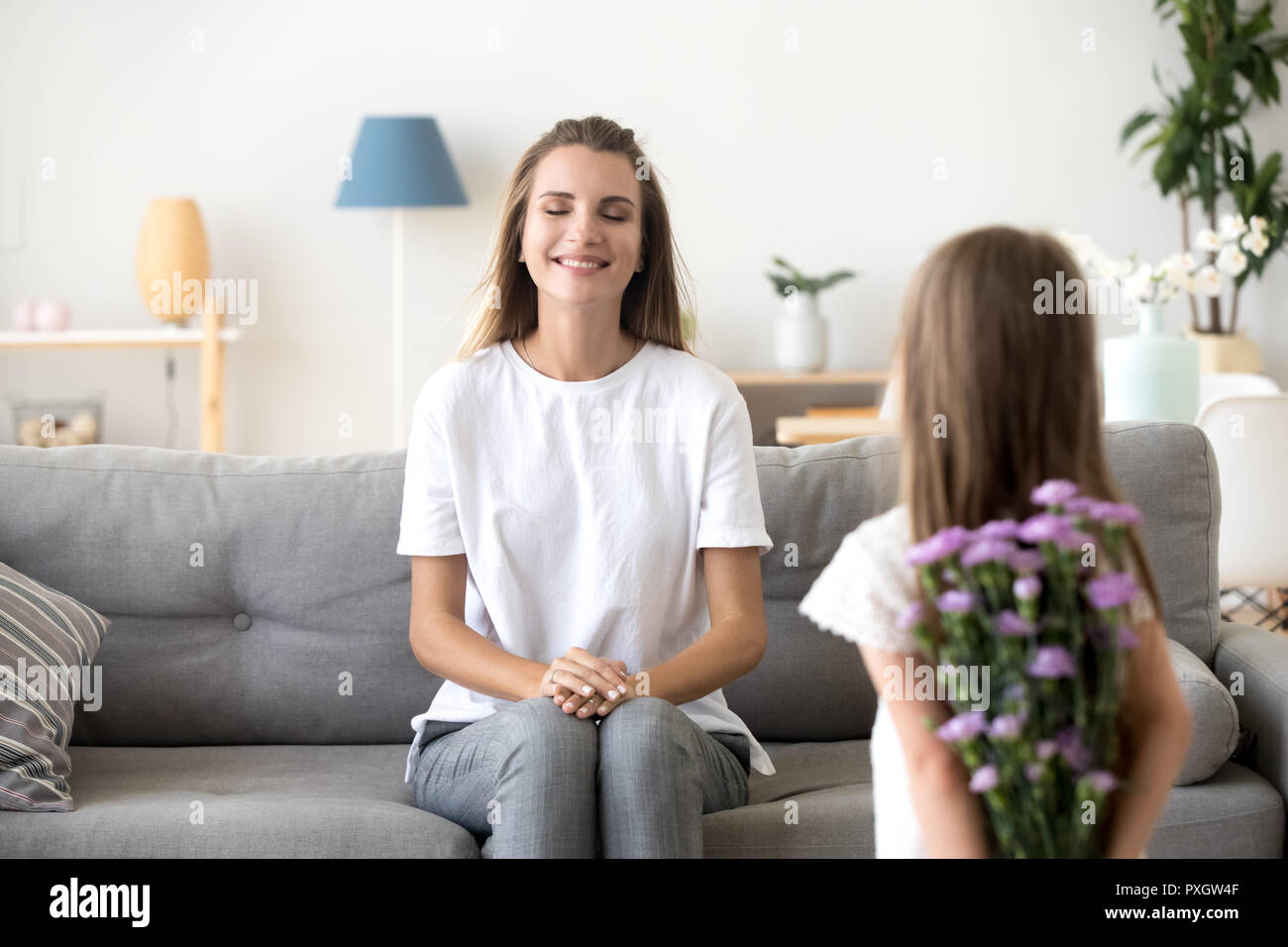 Piccola ragazza con fiori messa a sorpresa per la mamma Foto Stock