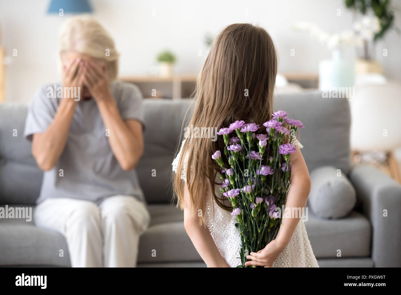 Bambina rendendo sorpresa per la nonna holding fiori Foto Stock