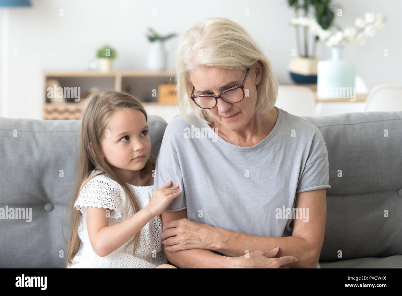 Carino nipote abbraccio triste nonna consolante lei a casa Foto Stock