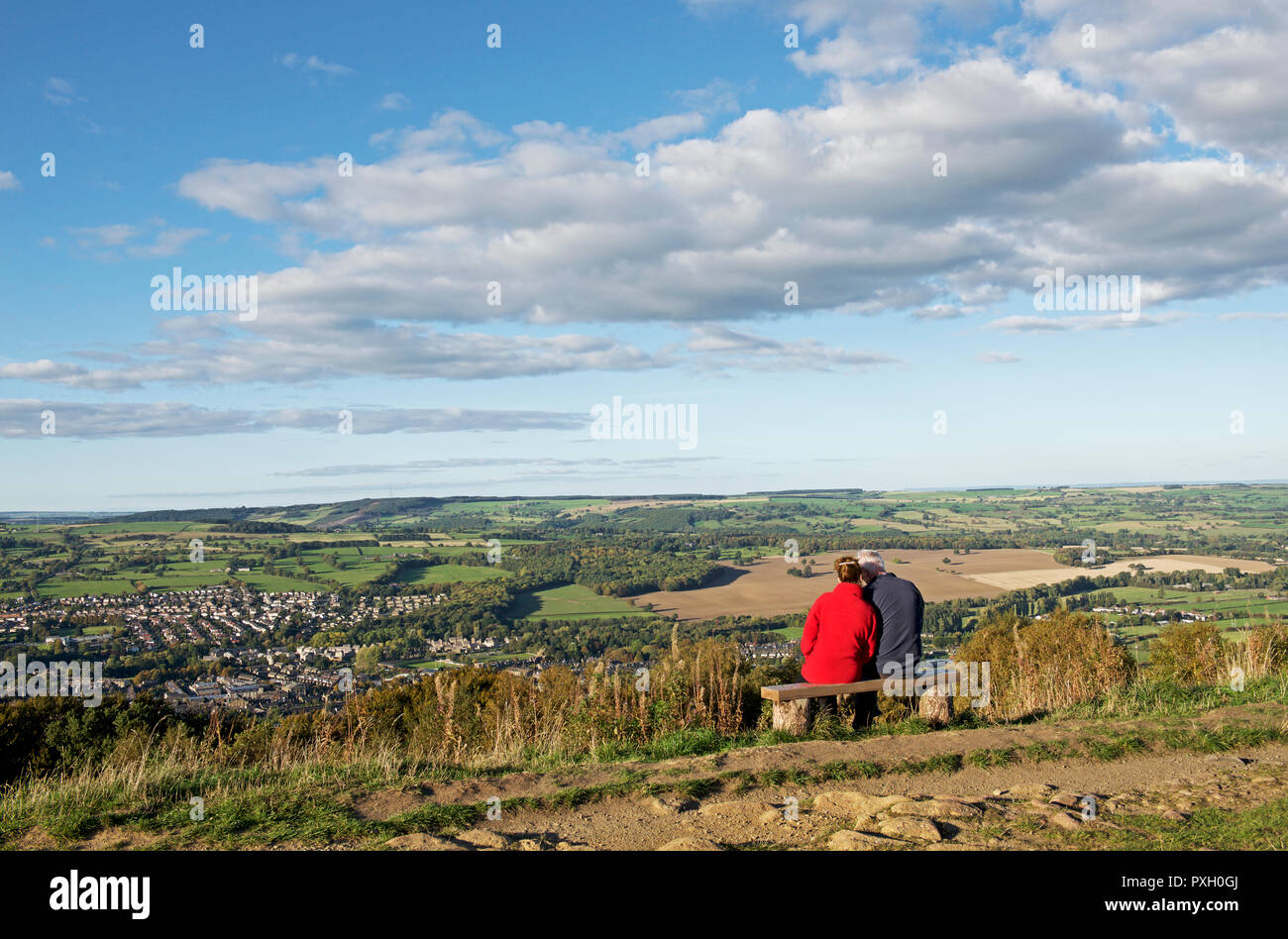 Giovane seduto su un banco di lavoro, sul Chevin, godendo della vista sulla Otley e abbassare Wharfedale, West Yorkshire, Inghilterra, Regno Unito Foto Stock