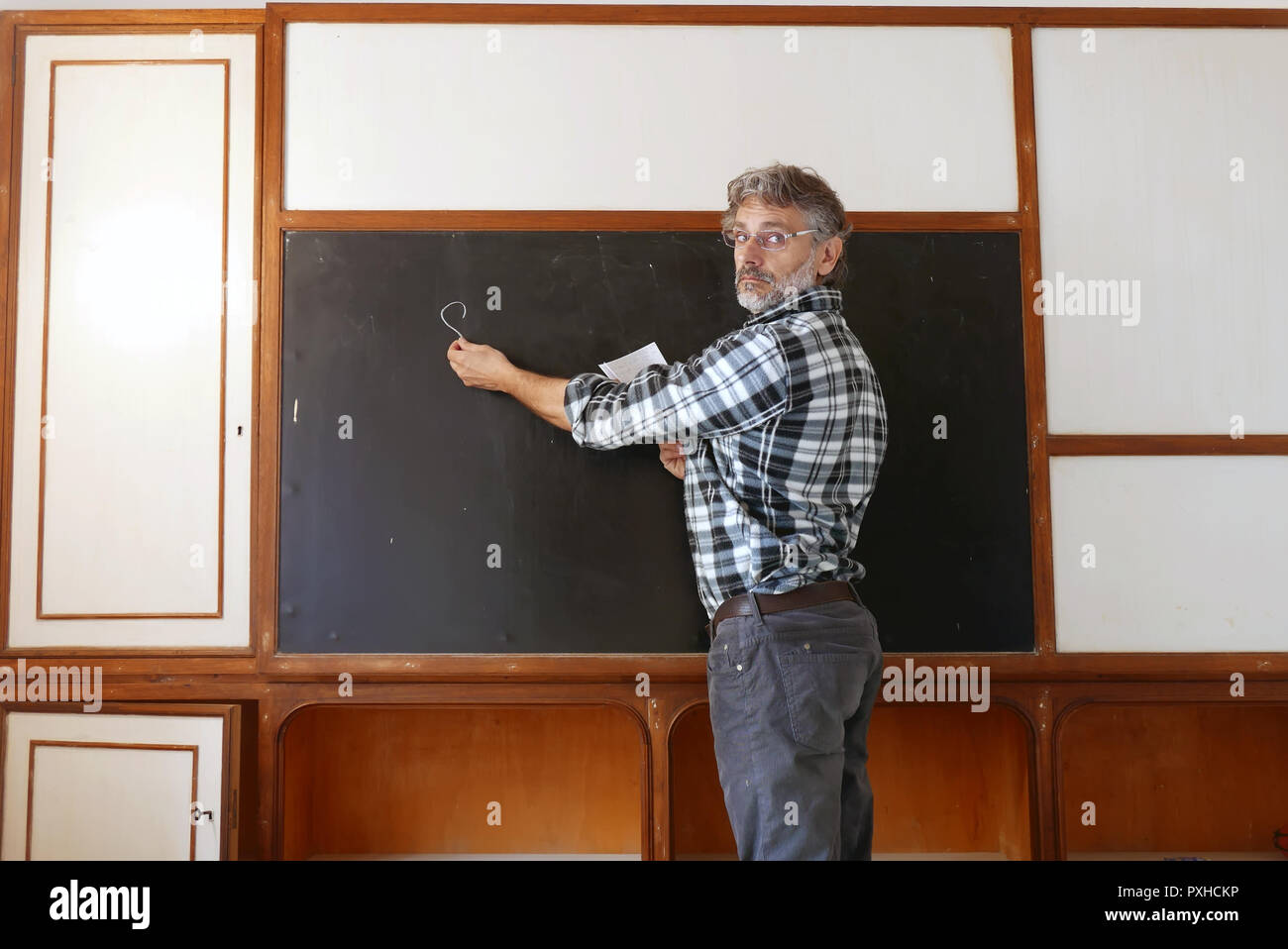 Insegnante nella classe scrivere sulla lavagna Foto Stock