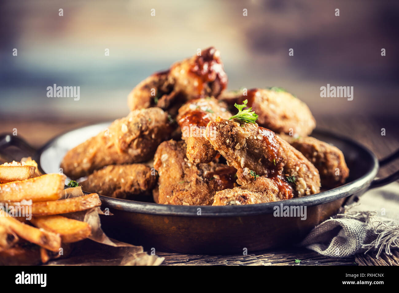Alette di pollo fritte con patate fritte sul tavolo in pub o ristorante. Foto Stock