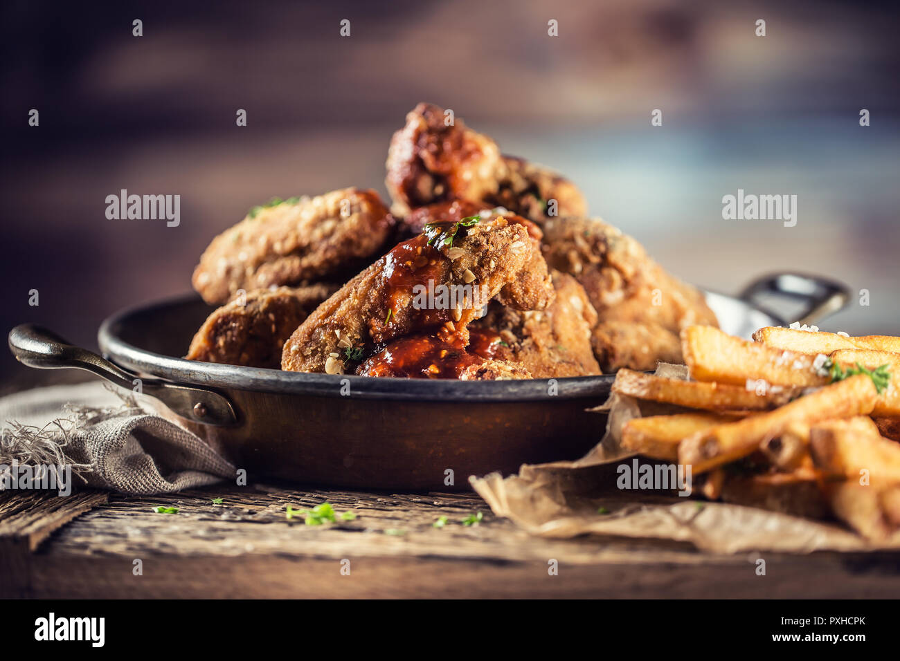 Alette di pollo fritte con patate fritte sul tavolo in pub o ristorante. Foto Stock
