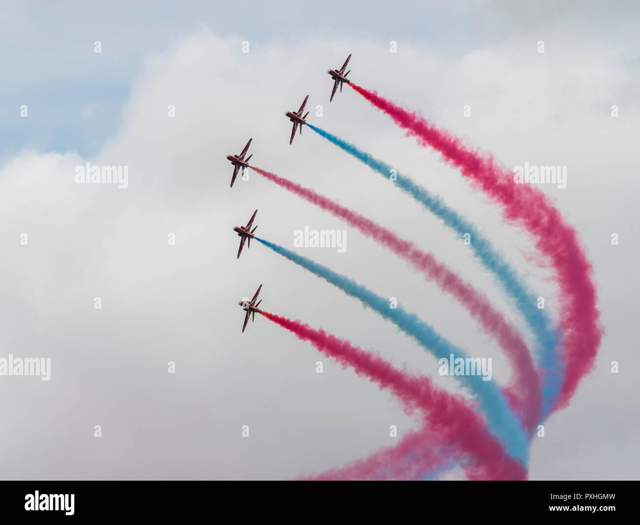 Rosso, bianco e blu fumo percorsi da frecce rosse aerobatic team display in volo sopra il castello di Highclere, Berkshire, Inghilterra Foto Stock