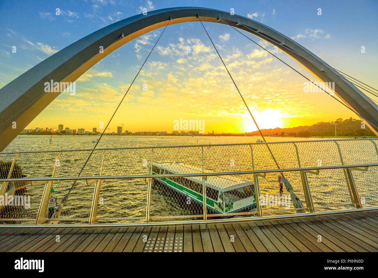 Città di interesse turistico in traghetto iconico Elizabeth Quay Bridge al tramonto sul fiume Swan. Scenic panorama visto dalla passerella di legno di forma arcuata ponte pedonale di Elizabeth Quay marina. Perth, Western Australia. Foto Stock