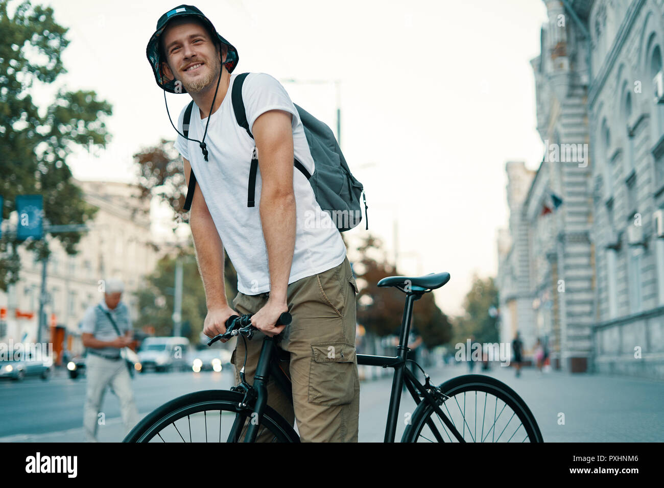 Un uomo in sella a una moto in una vecchia città europea all'esterno. Lo stile di vita, trasporti ecologici, persone concetto. Foto Stock