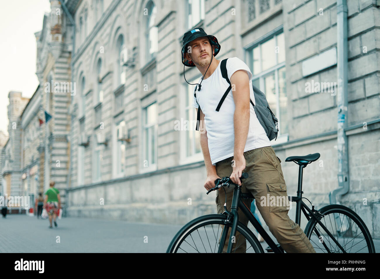 Un uomo in sella a una moto in una vecchia città europea all'esterno. Lo stile di vita, trasporti ecologici, persone concetto. Foto Stock